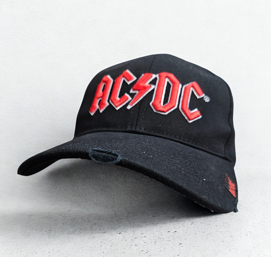 Black cap with red 'AC/DC' logo on a light gray background